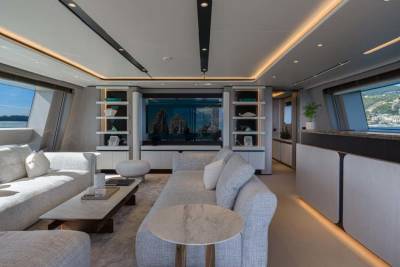 Luxurious yacht interior features plush seating, modern shelving, and panoramic views of a coastal town.