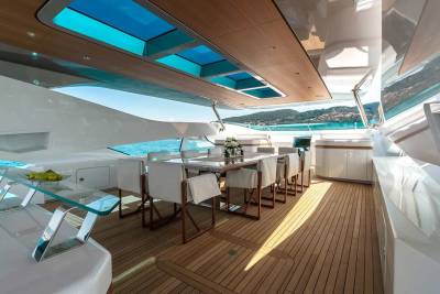 Luxurious yacht dining area with a table set for a meal, overlooking a stunning coastal landscape.