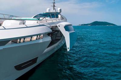 A sleek white yacht glides through the deep blue ocean, with lush green islands dotting the horizon under a clear sky.