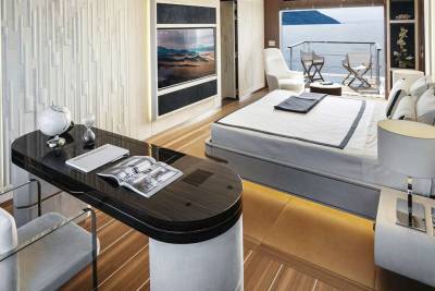Luxurious yacht cabin offers a sleek workspace and a comfortable bed with a stunning ocean view.