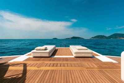 Relax on the sun-drenched deck of a luxury yacht, surrounded by the tranquil blue sea and distant, verdant islands.