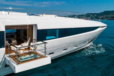 A sleek white yacht glides through the azure waters, offering a glimpse of its luxurious interior and outdoor seating area.