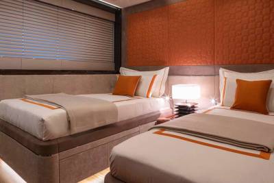 Luxurious twin beds with crisp white linens and warm orange accents create a serene retreat.