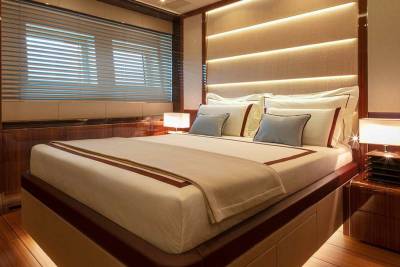Luxurious yacht cabin features a plush bed, ambient lighting, and rich wood finishes for ultimate comfort.