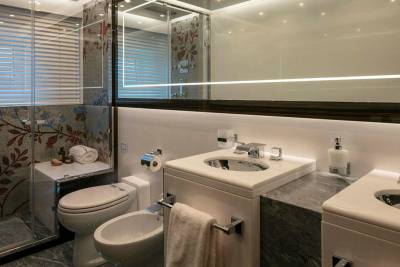 This luxurious bathroom features a mosaic-tiled shower, a modern bidet and toilet, and a sleek double vanity with chrome fixtures.