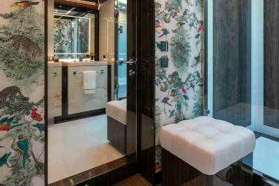 A luxurious bathroom features vibrant jungle-themed wallpaper and a sleek glass shower enclosure.