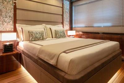 Luxurious yacht stateroom features a plush bed, elegant wood finishes, and ambient lighting for ultimate comfort.