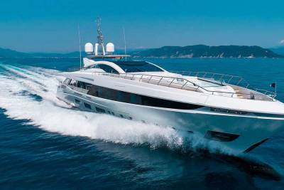 A sleek white yacht cuts through the deep blue ocean, leaving a powerful wake under a clear sky.