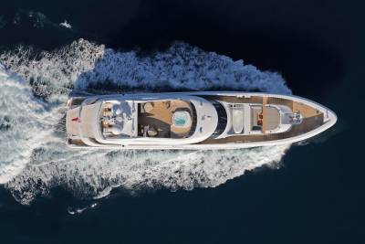 A luxurious yacht glides through the deep blue ocean, leaving a trail of white foam in its wake.