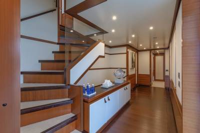 A luxurious yacht hallway features a striking wooden staircase and elegant cabinetry.