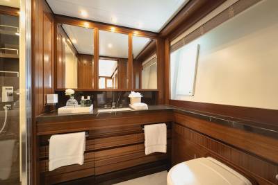 Luxurious wood paneling and marble accents create an opulent atmosphere in this yacht's elegant bathroom.