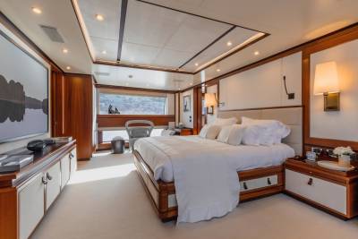 Luxurious yacht stateroom offers a serene retreat with plush bedding, elegant wood finishes, and scenic ocean views.