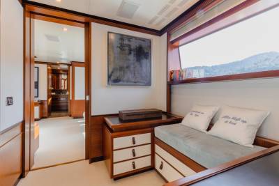 A cozy cabin nook with a view of rolling hills features plush pillows and a collection of books.