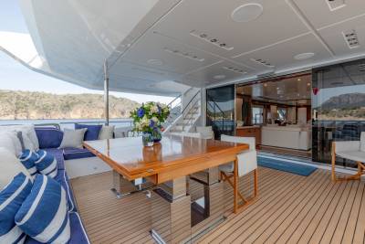 Dine al fresco on this luxurious yacht deck, surrounded by stunning coastal views and plush seating.