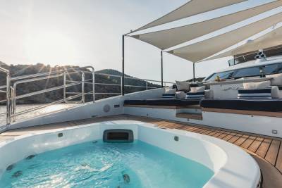 Relax in the jacuzzi on the deck of this luxurious yacht, surrounded by stunning coastal scenery.