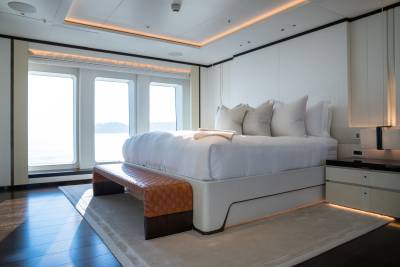 Luxurious yacht stateroom offers serene ocean views through expansive windows and elegant, modern furnishings.