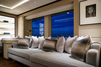 A plush sofa with decorative pillows offers a cozy view of the twilight sky through expansive windows.