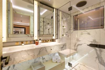Luxurious marble adorns this modern yacht bathroom, featuring a spacious shower and elegant dual sinks.