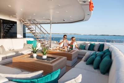 A couple enjoys drinks and a meal on the luxurious deck of a yacht, surrounded by the tranquil blue ocean.