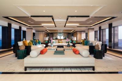 Luxurious yacht interiors feature plush seating, vibrant accent pillows, and floor-to-ceiling windows offering ocean views.