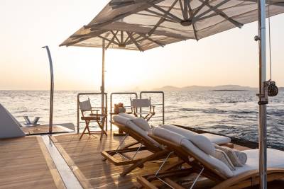 Relax on the deck of a luxury yacht as the sun sets over the tranquil sea.