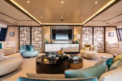 Luxurious yacht interior features plush seating, a large television, and stunning ocean views through panoramic windows.