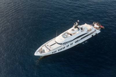 A luxurious white superyacht glides through the deep blue ocean, its sleek design cutting through the calm waters.