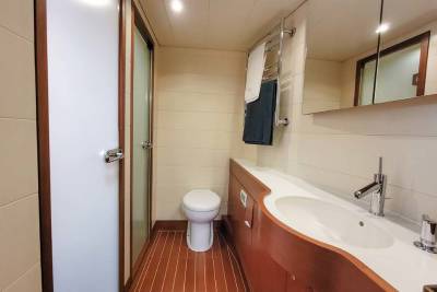 A sleek, modern bathroom with a white sink, wooden cabinetry, and a toilet is illuminated by soft ceiling lights.