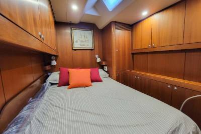 A cozy cabin bedroom features a comfortable bed adorned with colorful pillows and surrounded by rich wood cabinetry.