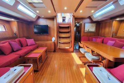 The warm wood interior of this yacht features plush seating, a dining area, and a television for comfortable cruising.