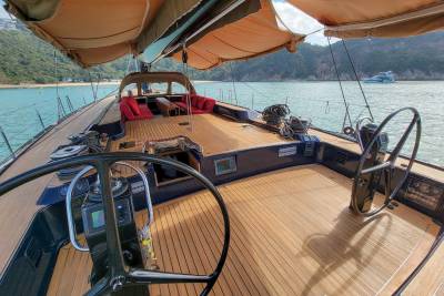 The sun-drenched deck of a luxurious yacht offers a serene escape amidst tranquil turquoise waters and lush green hills.
