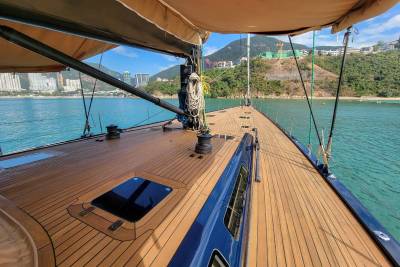 The sun-drenched deck of a luxurious yacht offers a serene vantage point of a tranquil bay dotted with distant cityscapes.