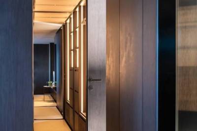 A modern hallway with warm lighting and sleek wood paneling creates an inviting and sophisticated atmosphere.