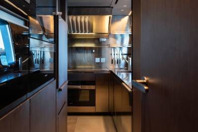 A sleek, modern galley kitchen gleams with stainless steel and rich wood cabinetry aboard a luxurious yacht.