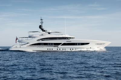 The sleek white yacht Arkadia glides through the deep blue ocean under a clear sky.