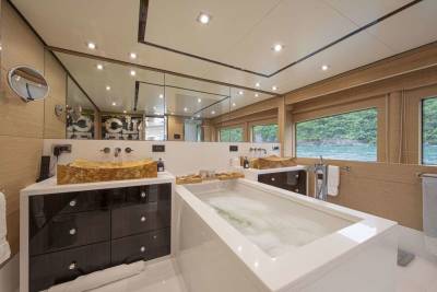 Luxurious yacht bathroom features a deep soaking tub and unique stone vessel sinks with stunning ocean views.