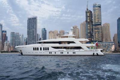 A luxurious white yacht glides through the choppy waters of a modern city skyline at dusk.