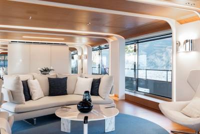 Luxurious yacht interiors feature a curved sofa, modern armchairs, and panoramic windows overlooking the sea.