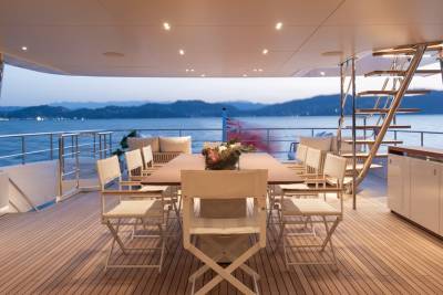 Dine al fresco on the deck of this luxury yacht as the sun sets over the tranquil sea and distant mountains.