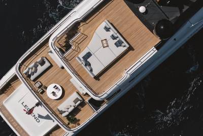 A luxurious yacht named "Legend" glides through dark, rippling waters, its spacious deck offering ample lounging areas.