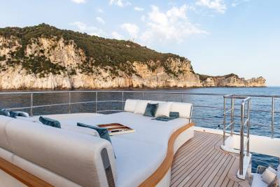 Luxurious yacht deck seating offers a serene spot to admire rugged coastal cliffs and the sparkling blue sea.