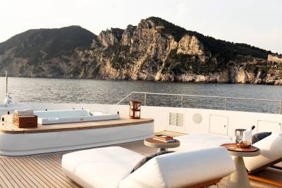 Relax in the jacuzzi or on a sun lounger aboard this luxurious yacht with a stunning coastal mountain backdrop.