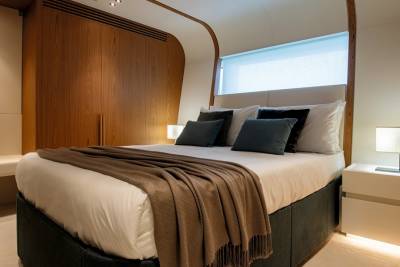A luxurious bedroom features a plush bed adorned with a warm throw and elegant pillows, complemented by rich wood paneling and a modern bedside lamp.