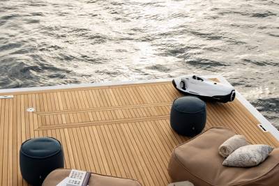 A sleek white watercraft rests on a teak deck beside comfortable seating overlooking the shimmering ocean.