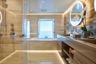 Luxurious marble bathroom with a soaking tub and a view of the ocean through a large window.