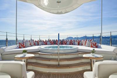Luxurious outdoor seating and a spa await on the deck of this elegant yacht, overlooking a serene ocean vista.
