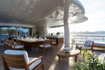 A luxurious yacht deck offers a stunning al fresco dining experience with a view of the serene sea and distant mountains.