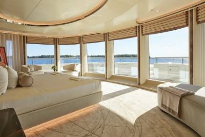 Luxurious yacht bedroom offers panoramic ocean views through expansive windows and a curved ceiling.