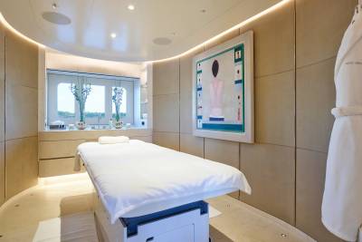 A luxurious spa room features a massage table, a serene painting, and a plush bathrobe hanging on the wall.