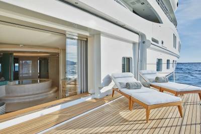 Relax on the sun-drenched deck of this luxurious yacht, with a private spa visible through the glass doors.